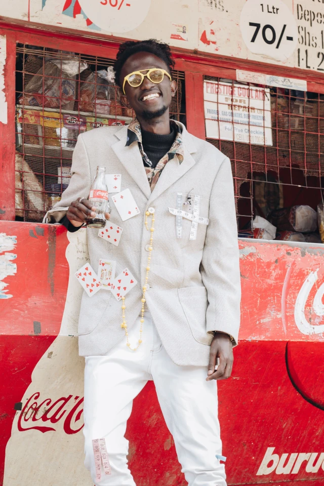 A man standing in front of a shop, with lots of Coca Cola signs on it. 