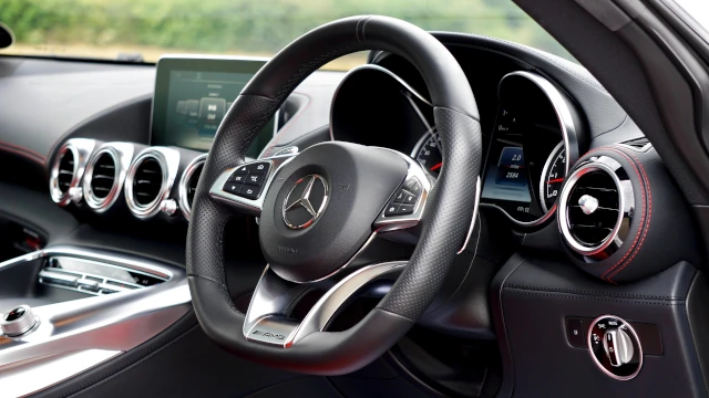 Close up of the Mercedes Benz logo on a steering wheel. 
