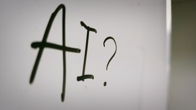 The phrase "AI?" written on a whiteboard.
